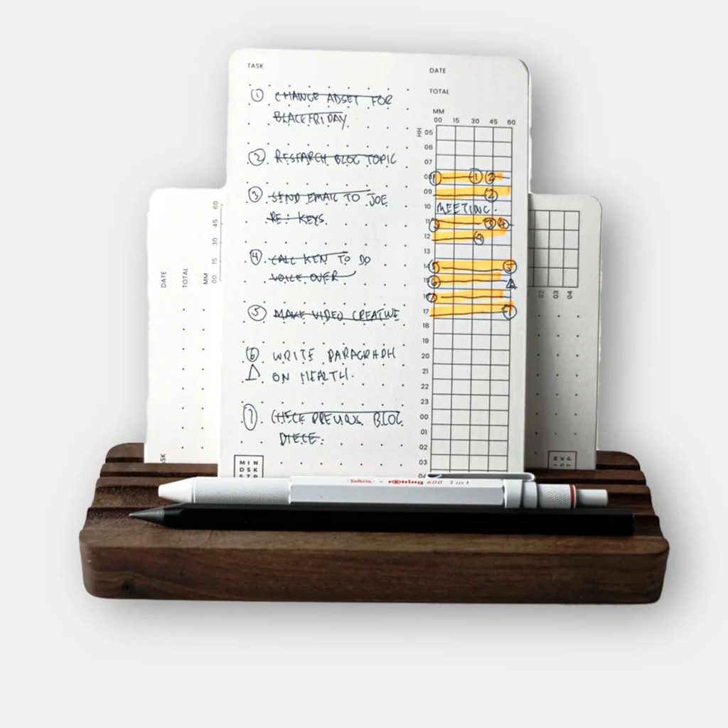 A wooden desk accessory with a card standing on it with tasks and timeslots marked